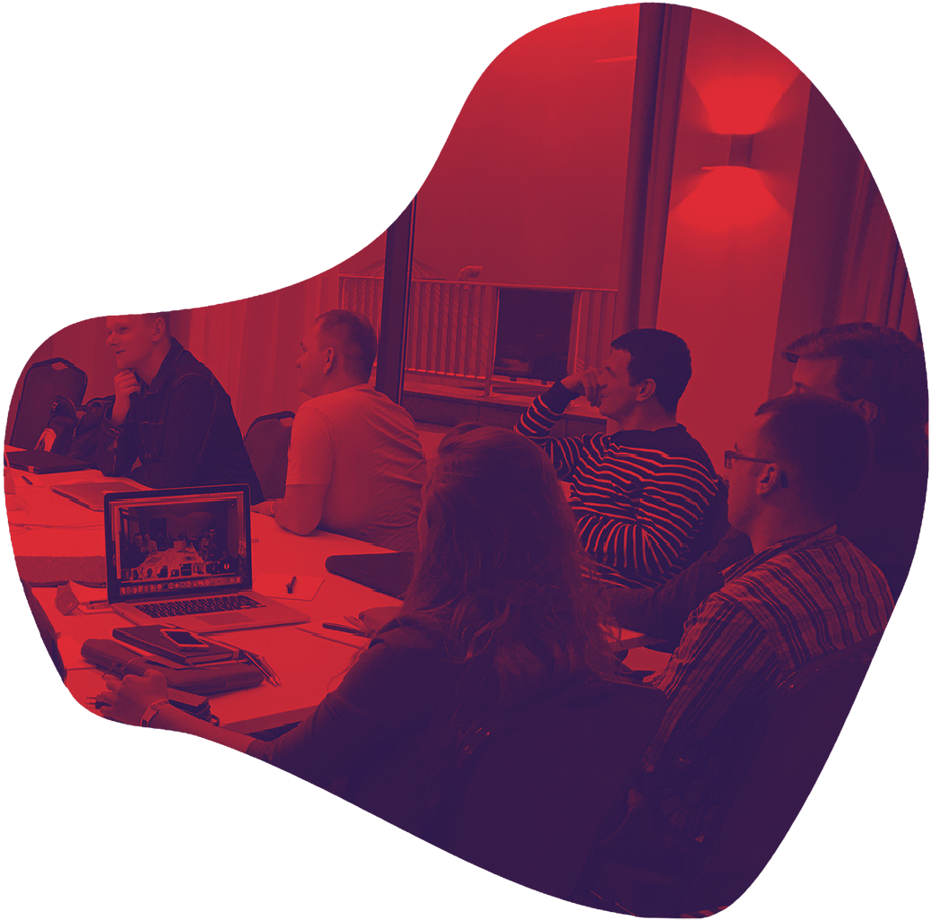 A group of people is sitting around a conference table in a meeting room.